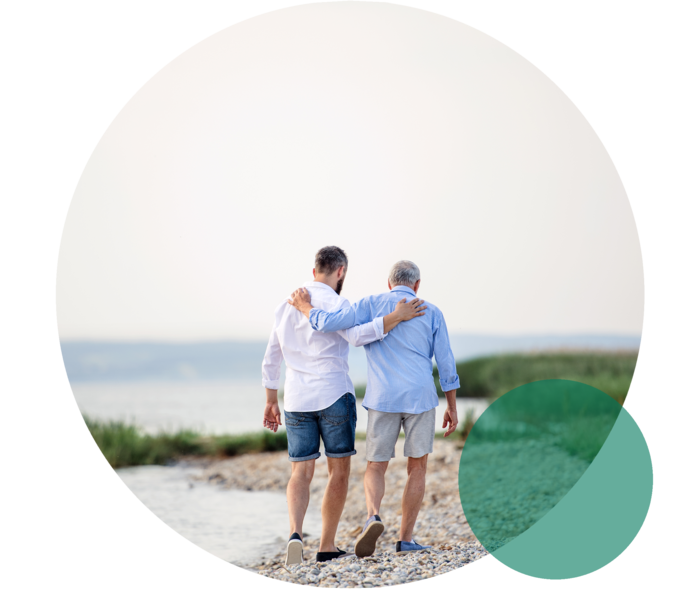 Das Bild zeigt Vater und Sohn am Strand spazieren