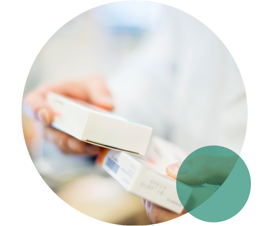 Hände einer Person mit weißem Kittel halten zwei Medikamentenschachteln.