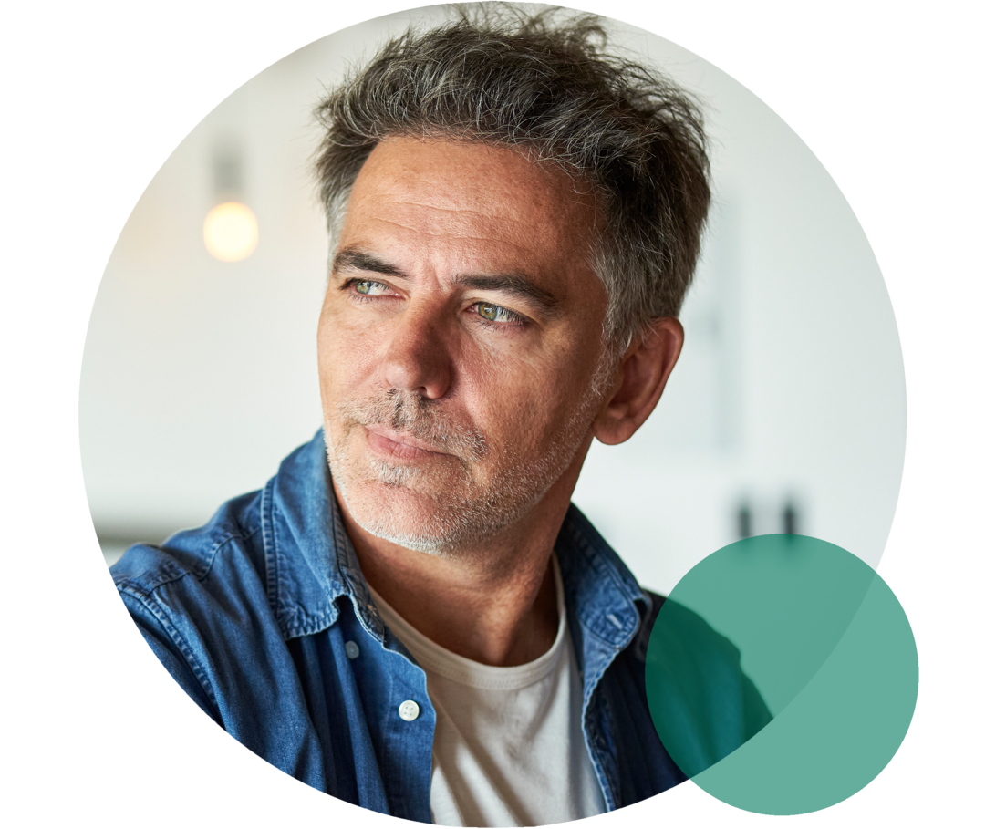 Mann mit ergrautem Haar und Dreitagebart blickt nach links.