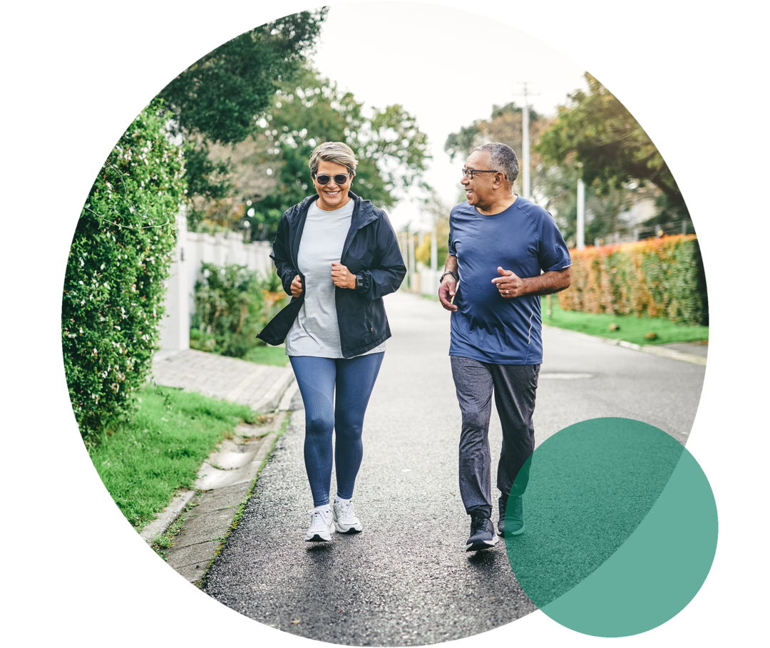 Eine Frau und ein Mann höheren Alters in Sportkleidung. Sie joggen gemeinsam auf einer Straße.