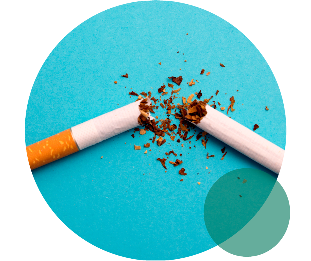 Eine zerbrochene Zigarette auf türkisem Grund. Tabak liegt rund um die Bruchstellen.