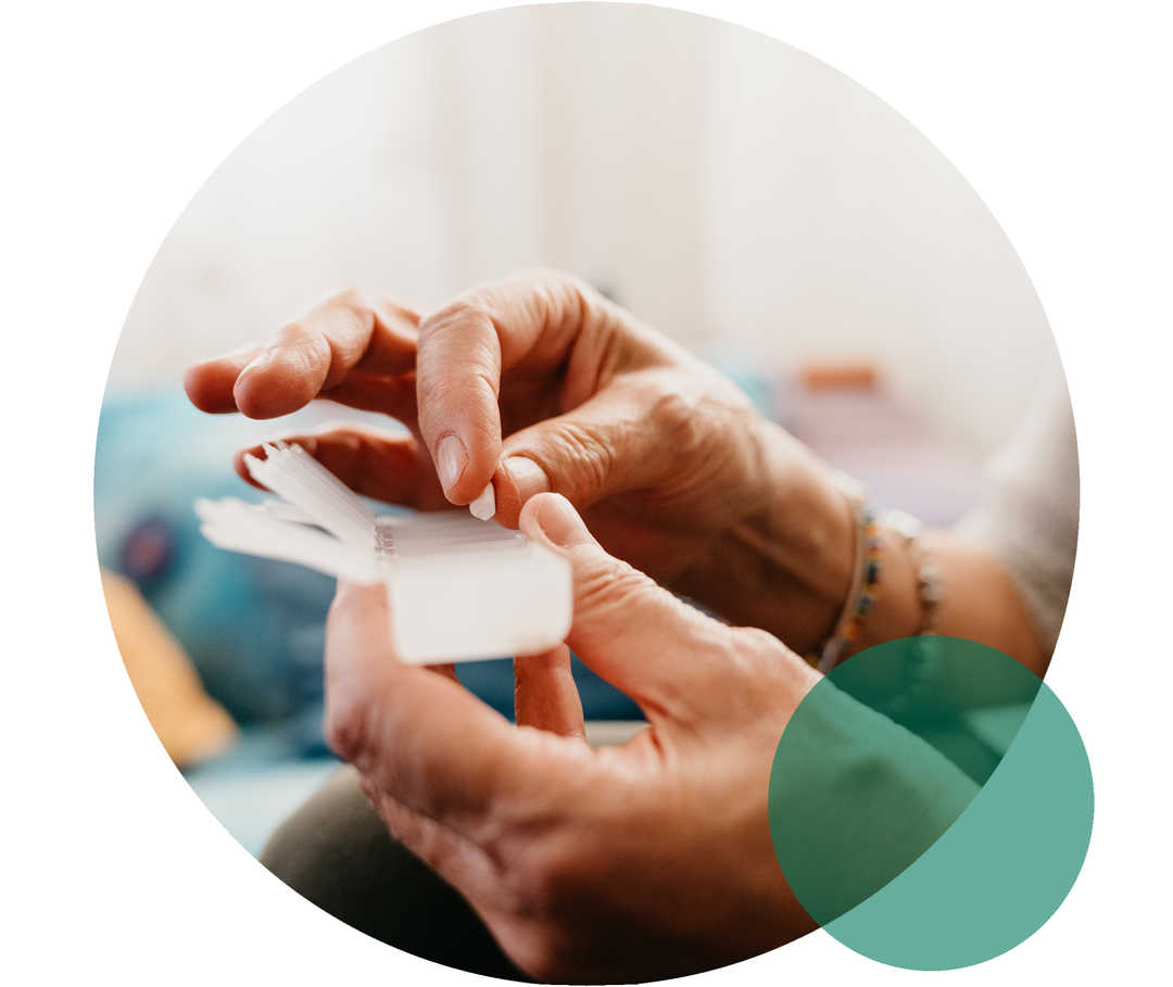 Seniorin hält eine Pillendose in der Hand, in die sie Medikamente einsortiert.