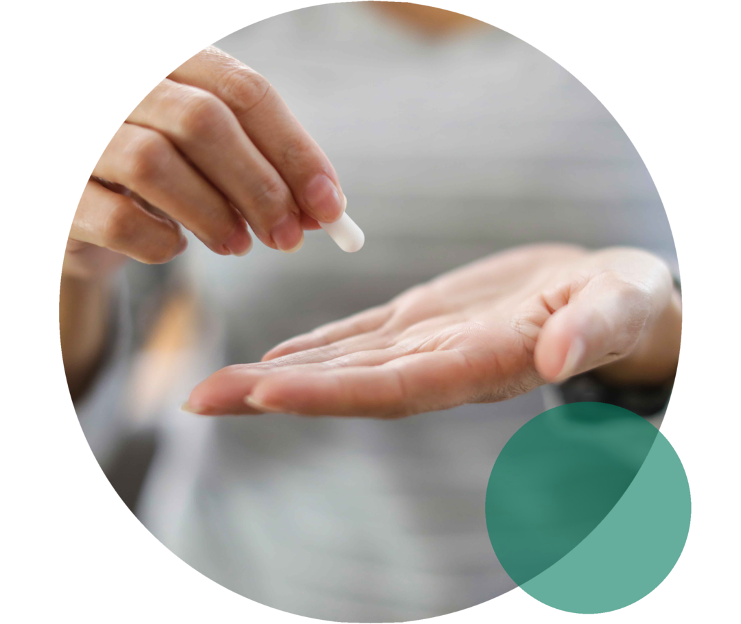 Hände einer Person. Eine Hand hält eine weiße Tablette.